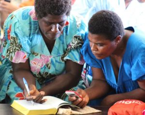 May, 2016: Women of the Paama language group in Vanuatu listen to a MegaVoice player while following the text in their newly dedicated print volume of the New Testament