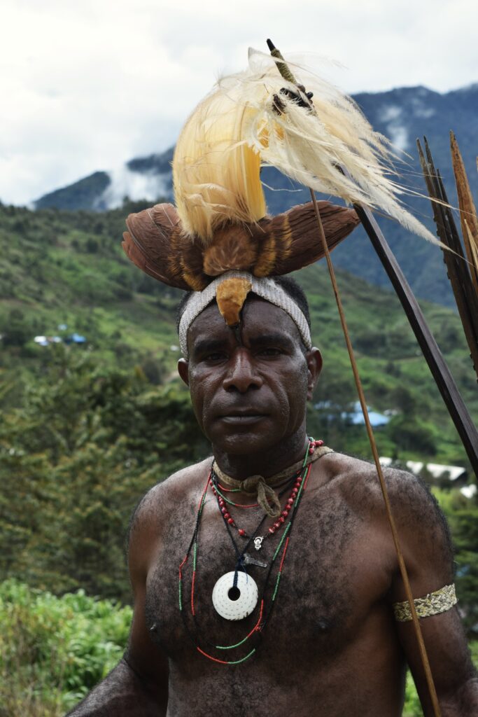 A Ketengban man from Indonesia in ceremonial garb holding a spear looks at the camera