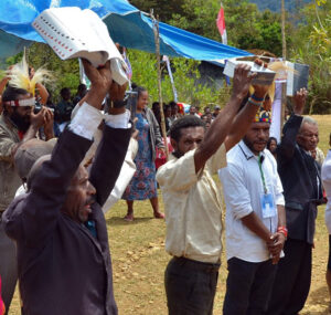 Pastors and elders hold their new Bibles high in celebration